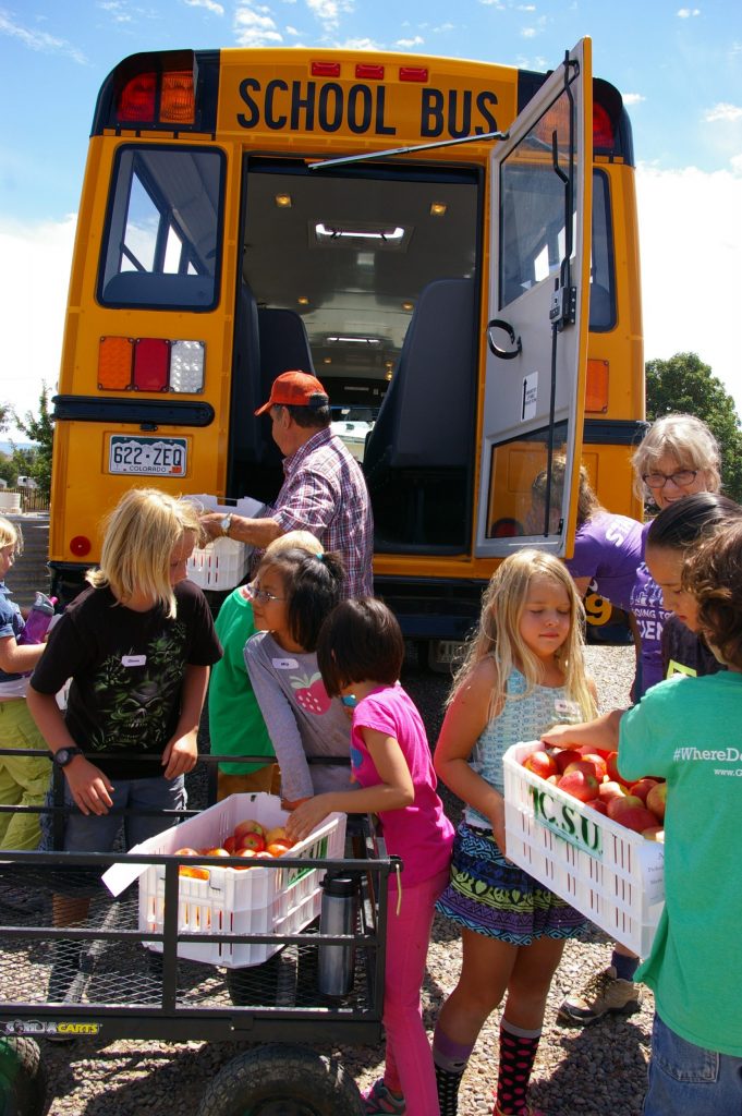 students loading harvested food into a school bus